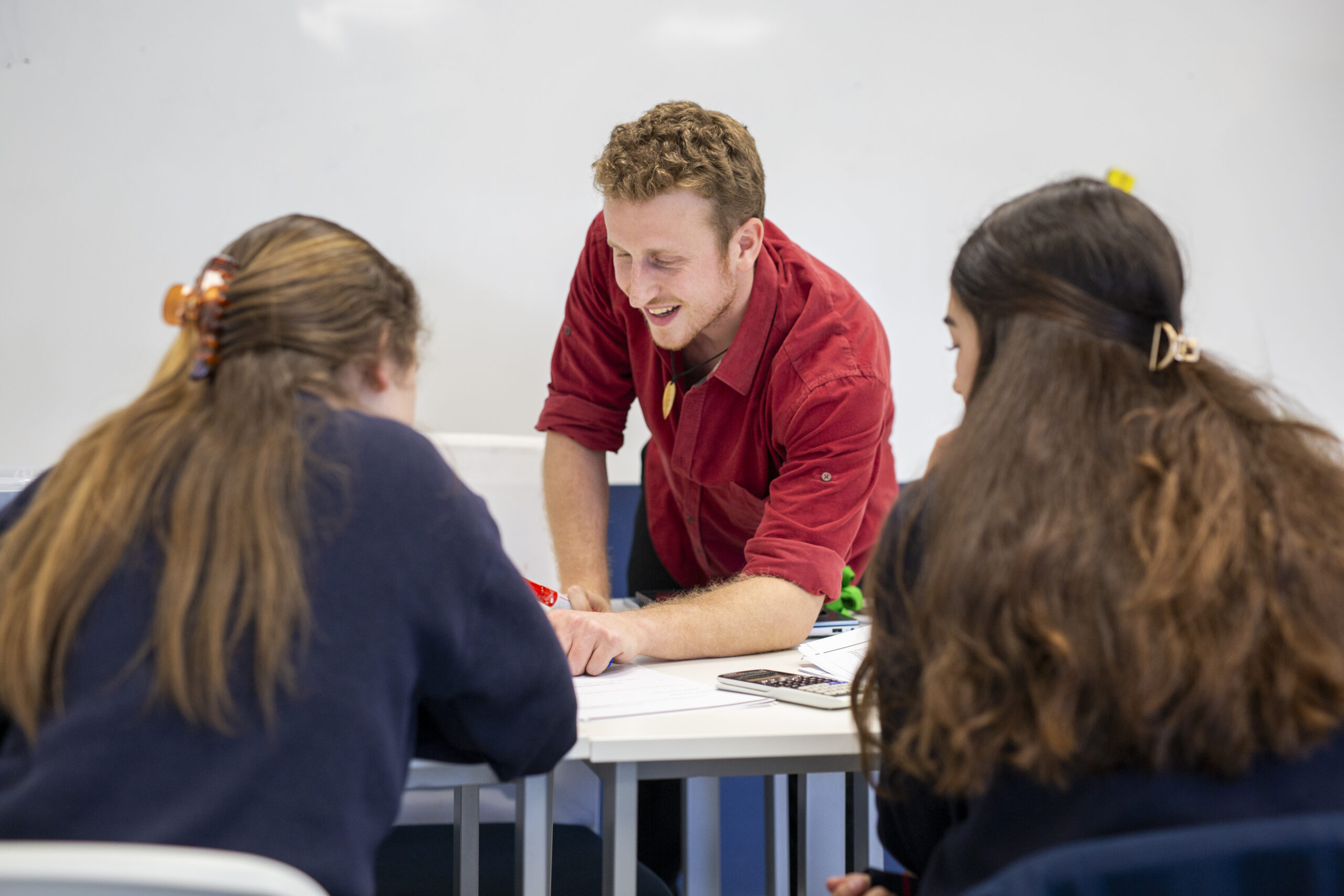 Profesor de Think Ahead Academy ayudando a dos alumnas en clase